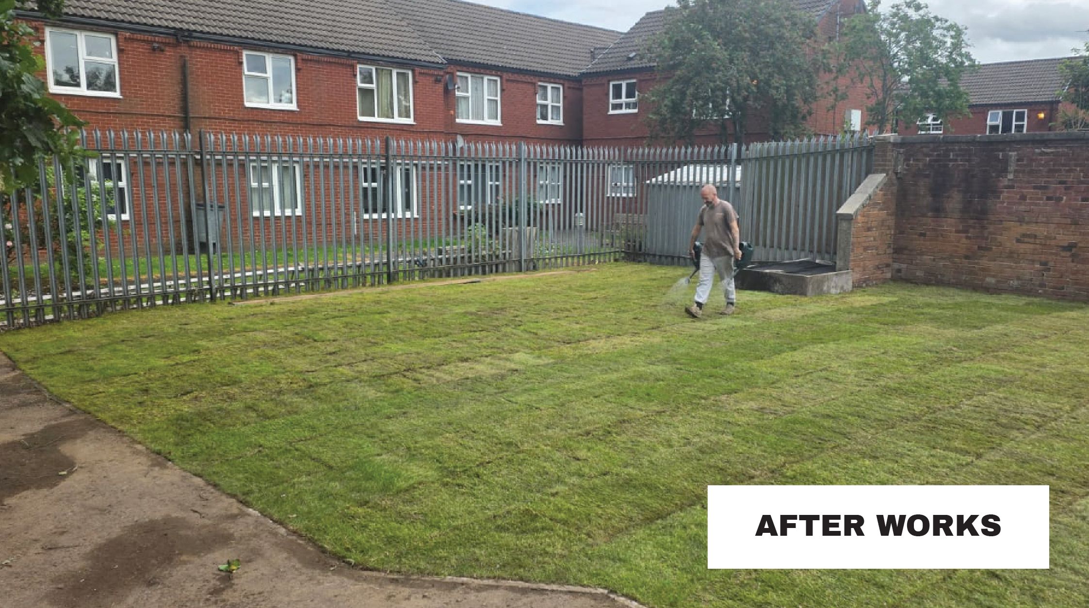 A worker watering newly laid grass beside homes at Collin Avenue, Manchester, after improvement works