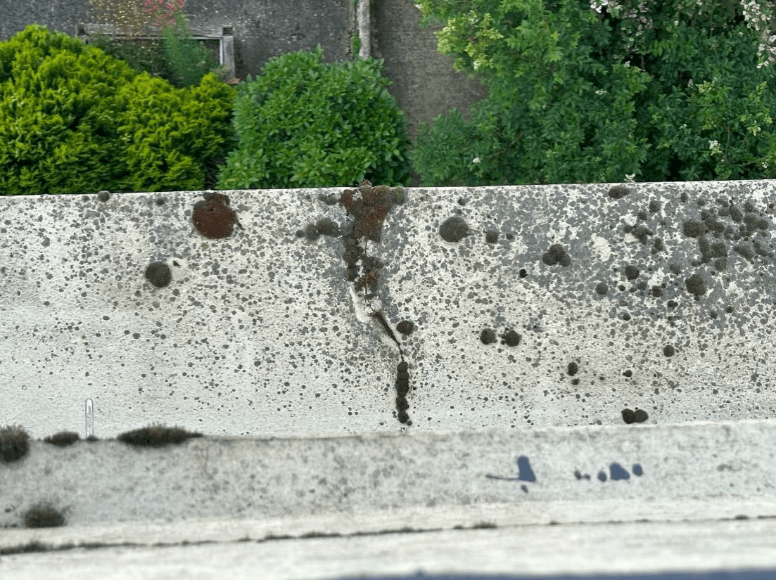 Cracked, lichen-covered parapet wall overlooking gardens at Pembridge Gardens